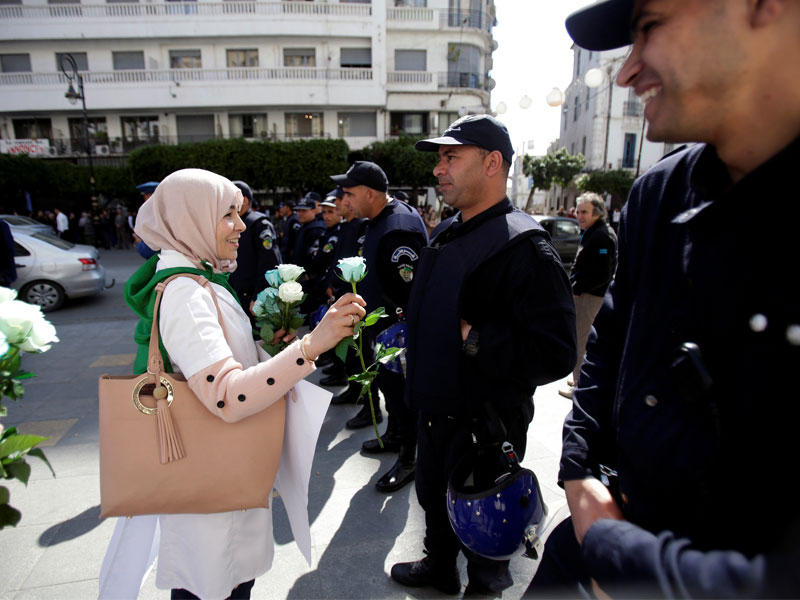 متظاهرة توزع زهوراً على رجال الأمن خلال مسيرة احتجاجية للأساتذة والطلاب في العاصمة الجزائرية أمس  (رويترز)