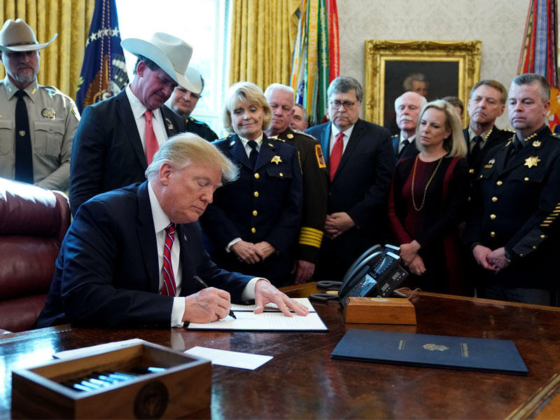 ترامب يوقع الفيتو بحضور فريقه الرئاسي في المكتب البيضاوي بالبيت الأبيض أمس الأول (رويترز) 