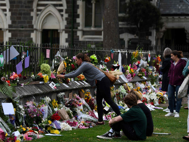 متضامون مع ضحايا الهجوم يضعون زهوراً ويضيئون شموعاً على سور أحد المسجدين المستهدفين في كرايستشيرش أمس t(أ ف ب)