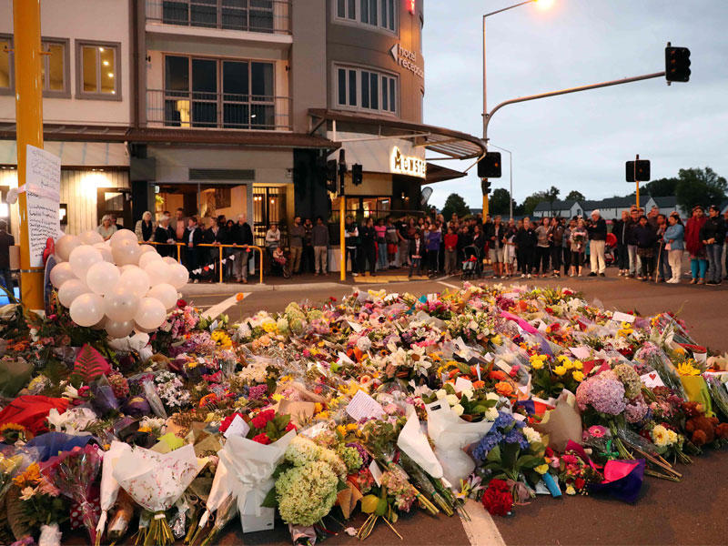 متضامنون مع ضحايا الهجوم يضعون زهوراً ويضيئون شموعاً على سور أحد مسجدَي المجزرة في كرايستشيرش أمس (أ ف ب)