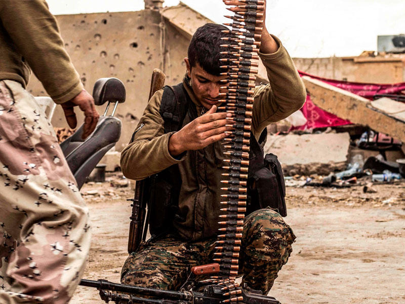 مقاتل كردي يجهز ذخيرة سلاحه في الباغوز يوم الجمعةt(أ ف ب)