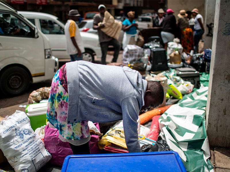 الناس ينتظرون مع البضائع الموجودة على جانب الطريق في وسط جوهانسبرج لالتقاطها بواسطة (الناقلون) لنقلها عبر الحدود إلى زيمبابوي