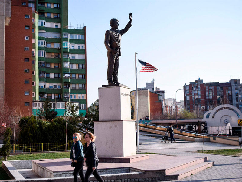 ألبان كوسوفو يمشون أمام تمثال الرئيس الأمريكي السابق بيل كلينتون