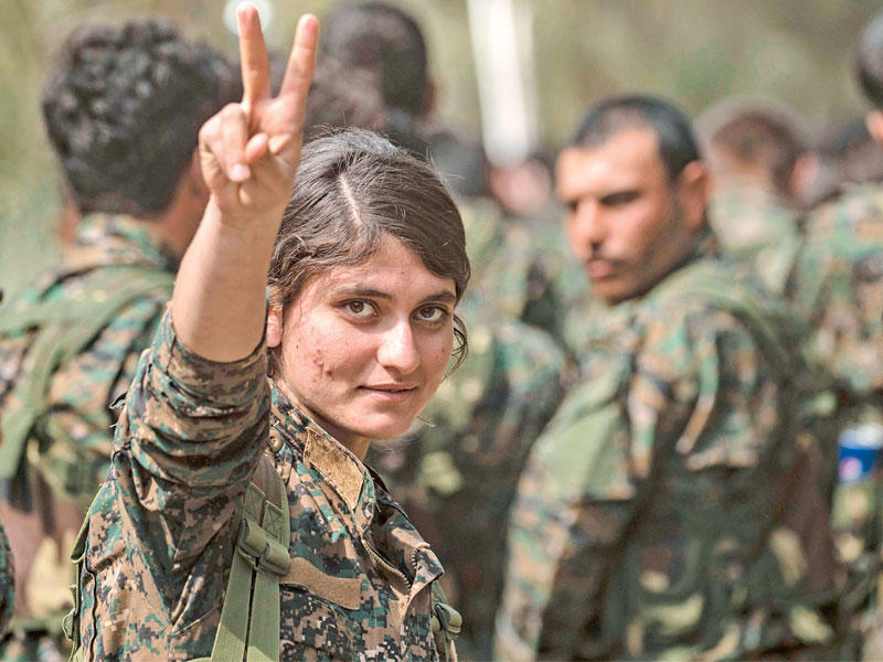 مقاتلة كردية ترفع شارة النصر في حقل العمر أمس (أ ف ب)