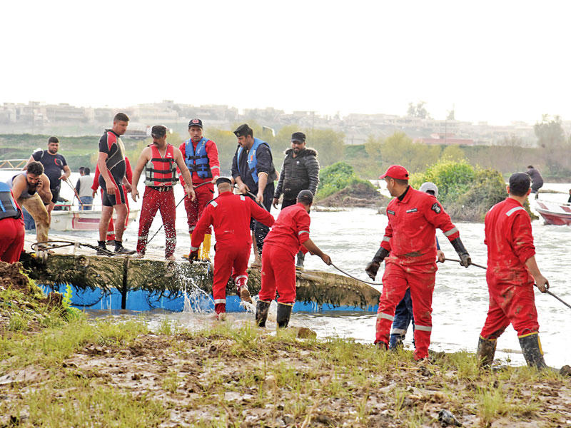 عاملو إغاثة عراقيون ينتشلون العبارة الغارقة في دجلة قبالة الموصل أمس الأول (أي بي ايه)