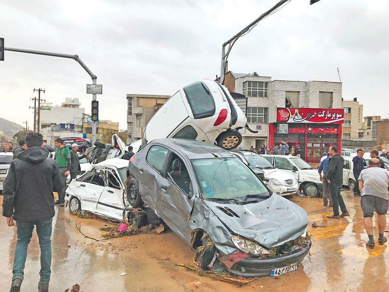 إيرانيون بمحيط سيارات جرفتها مياه السيول في شيراز أمسt(أ ف ب)