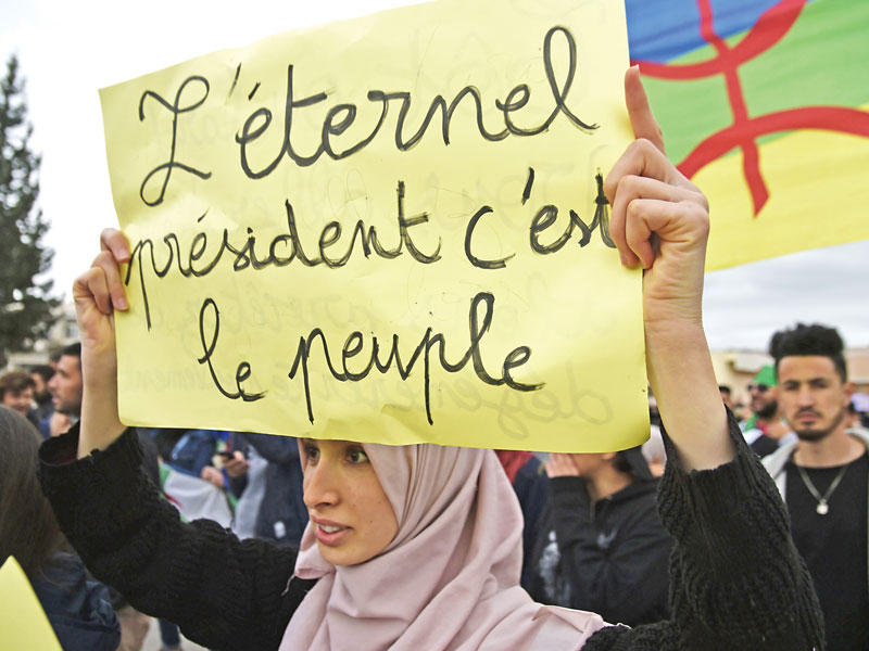 جزائرية تحمل لافتة كتب عليها بالفرنسية :«الشعب هو الرئيس الأبدي» خلال احتجاج ضد النظام في بجايا أمس الأول     (أ ف ب)