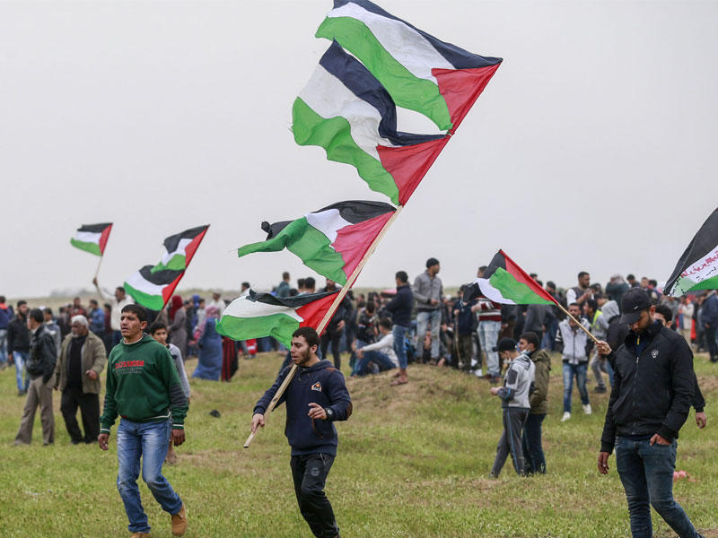 المتظاهرون الفلسطينيون يلوحون بالأعلام الوطنية خلال مظاهرة للاحتفال بالذكرى السنوية الأولى لاحتجاجات مسيرة العودة