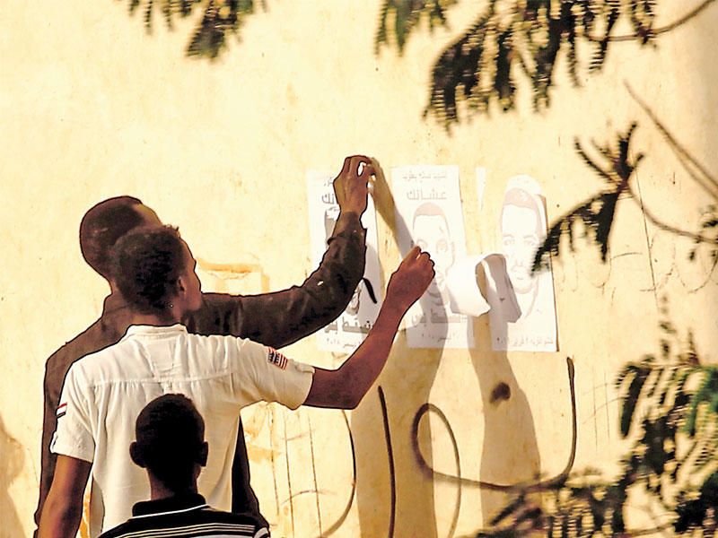 سودانيون مؤيدون للحكومة يزيلون ملصقات ضد النظام في الخرطوم          (أ ف ب)