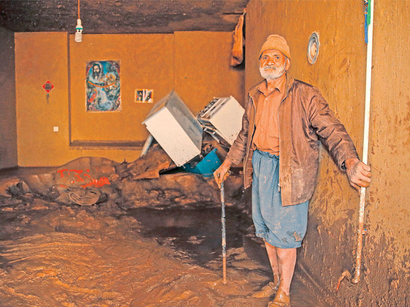 مسن إيراني اجتاحت السيول منزله في لورستان أمسt (أ ف ب)