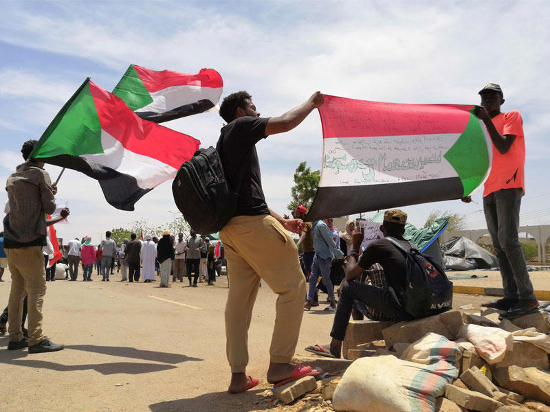 يحمل الشباب السوداني العلم الوطني أثناء تجمعهم في العاصمة الخرطوم