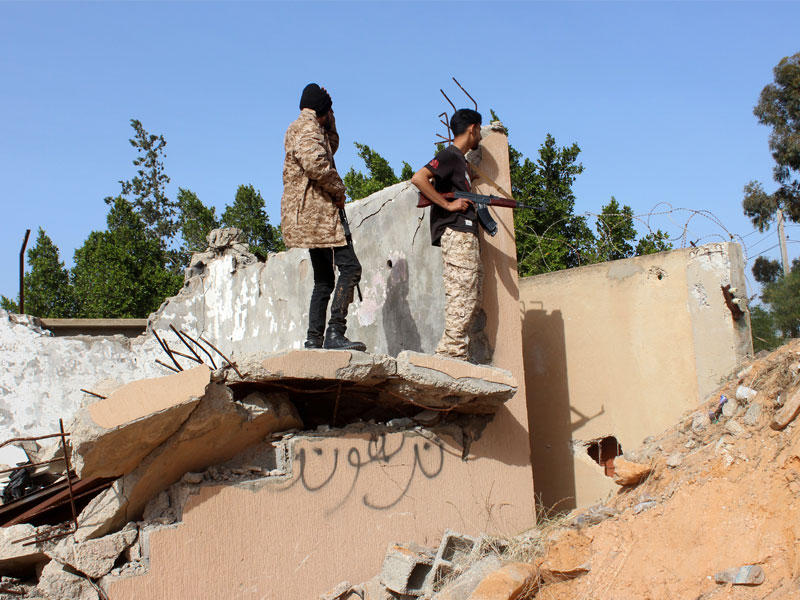 أفراد القوات الحكومية الليبية المعترف بها يراقبون مبنى مدمرا في منطقة خلة فرجان في طرابلس ، ليبيا