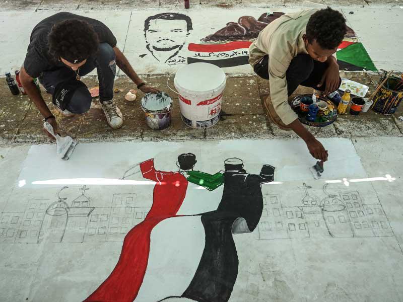 متظاهرون سودانيون يرسمون لوحة جدارية أثناء اعتصام خارج مقر الجيش في العاصمة الخرطوم