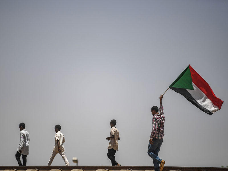 متظاهرون يرفعون علم بلادهم خلال اعتصامهم أمام مقرّ القيادة العامة في الخرطوم (أ ف ب)