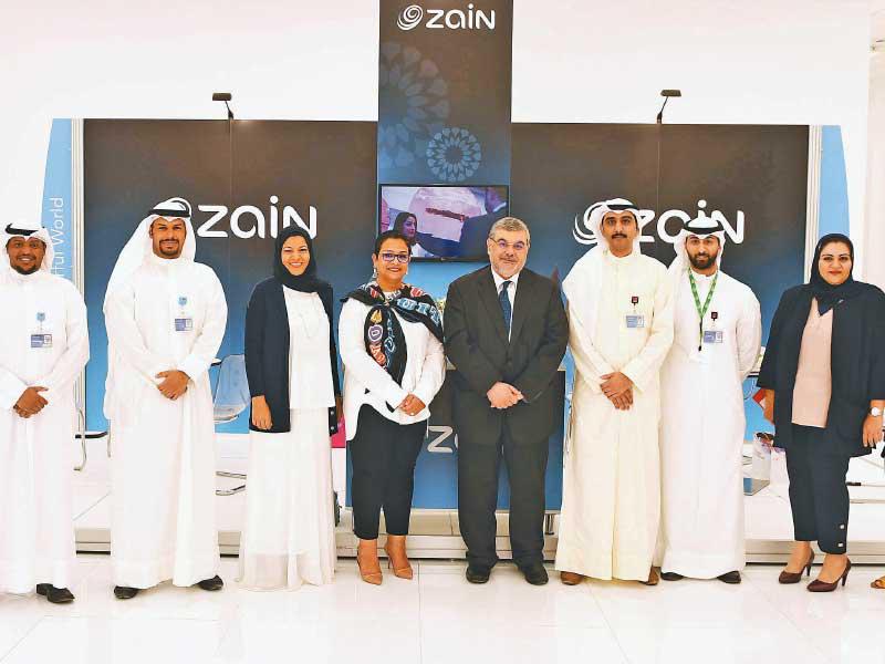 بورسلي تتوسط فريق «زين» في جناح الشركة بالمعرض 