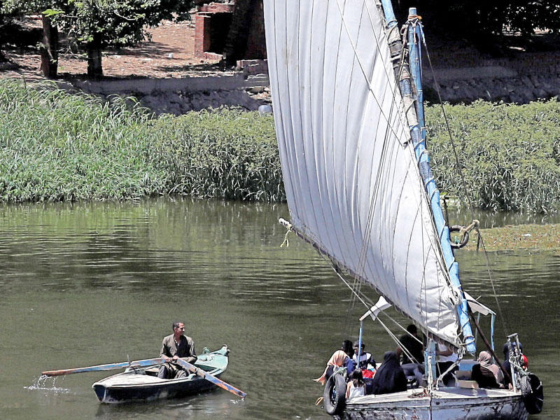 مزارع مصري يستخدم قارباً شراعياً في نهر النيل أمس (رويترز)
