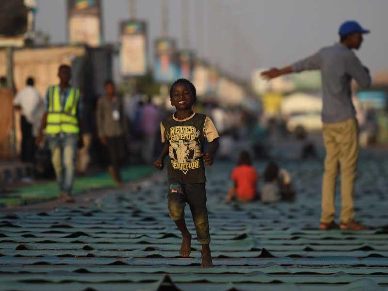 طفل سوداني يركض في شارع تصطف بالسجاد خارج مقر الجيش في الخرطوم