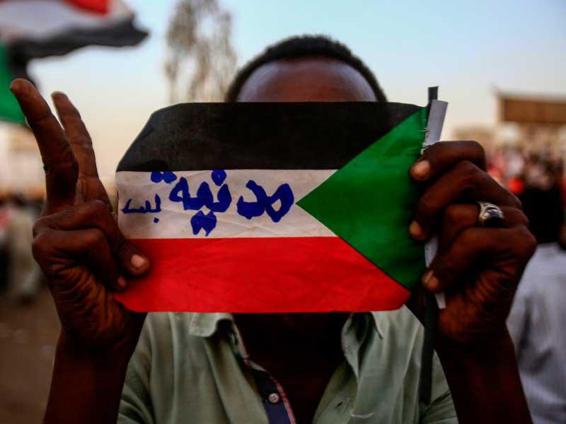 سوداني يرفع علماً كتب عليه «مدنية» خلال اعتصامه أمام مقر القيادة العامة في الخرطوم (أ ف ب)