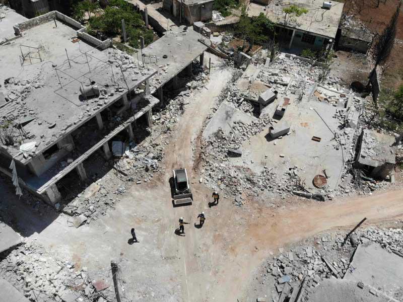 أفراد من الدفاع المدني السوري يزيلون الأنقاض لفتح الطريق