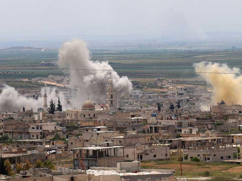 الدخان يرتفع فوق المباني أثناء قصف قوات النظام السوري وحلفائه على بلدة خان شيخون في محافظة إدلب