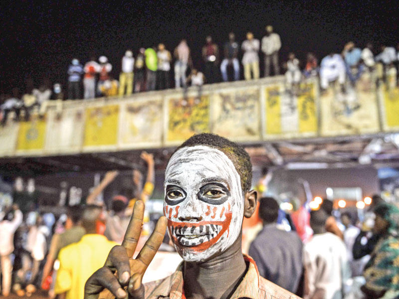 سوداني يرفع شارة النصر أمام مقر القيادة العامة       (أ ف ب)