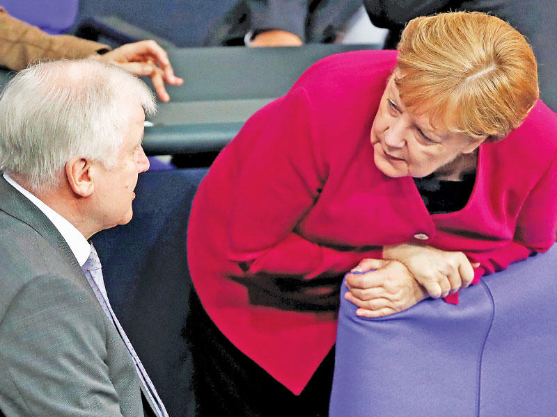 ميركل تتحدّث مع وزير الداخلية خلال جلسة للبرلمان في برلين أمس (رويترز)