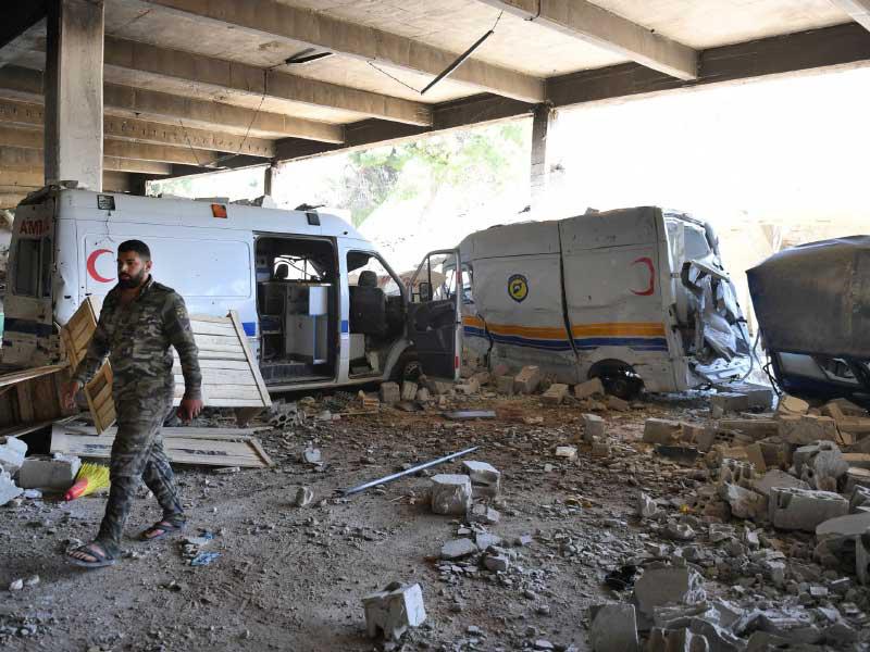 جندي سوري يسير بجوار سيارات الإسعاف المدمرة وسيارات الدفاع المدني السوري