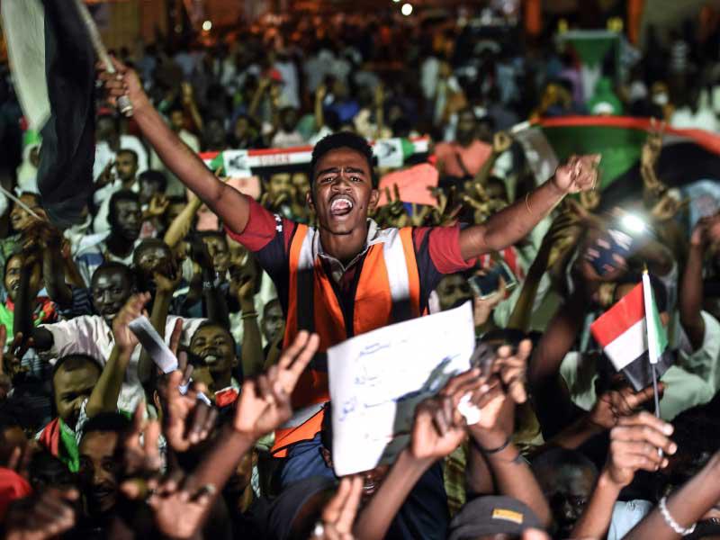 المتظاهرون السودانيون يلوحون بالأعلام وعلامات النصر السريعة وهم يتجمعون في اعتصام خارج المقر العسكري في الخرطوم