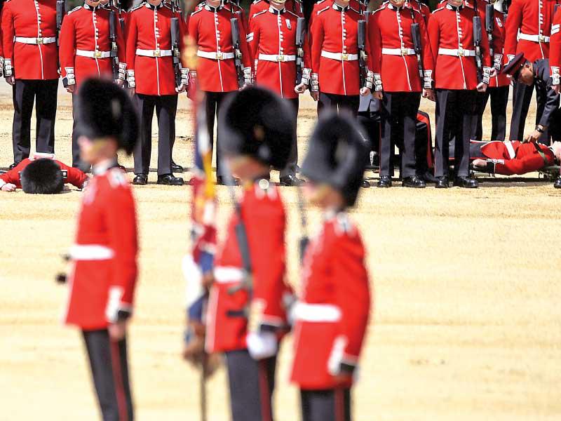 عناصر من حرس الملكة يفقدون الوعي أمس الأول خلال تدريبات في لندن على استعراض خاص بعيد ميلاد الملكة إليزابيث بعد أيام (رويترز) 