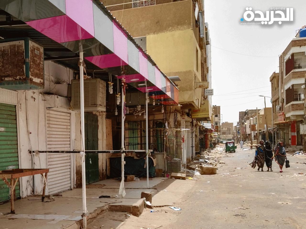 نساء سودانيات يتجولن في متاجر مغلقة في شارع مهجور في مدينة أم درمان التوأم بالخرطوم