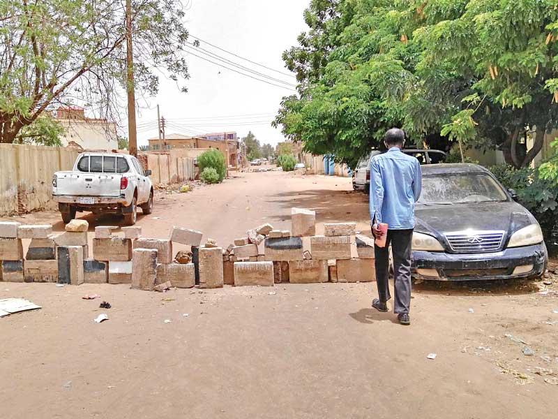 سوداني أمام حاجز أقامه المتظاهرون في أحد شوارع أم درمان (أ ف ب)