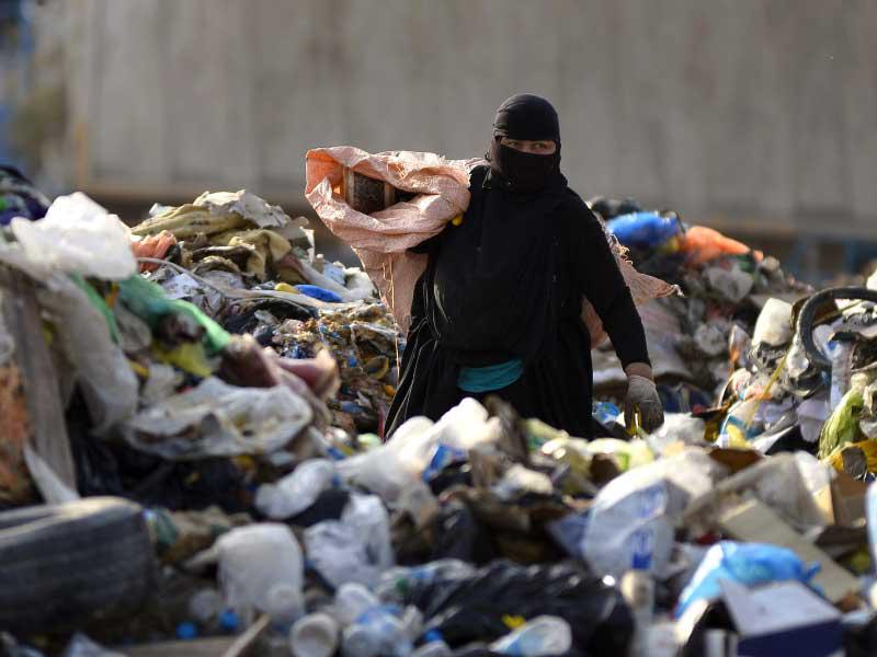 امرأة تجمع مواد قابلة لإعادة التدوير ليتم بيعها للحصول على دخل إضافي في مدينة النجف العراقية