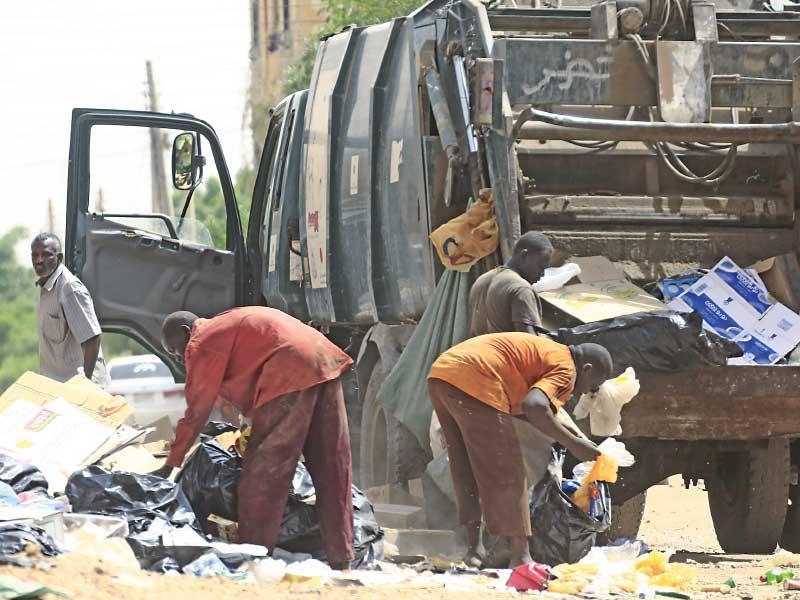 عمال ينظفون ساحة «اعتصام القيادة» في الخرطوم بعد أيام من فضه بالقوة  (أ ف ب)