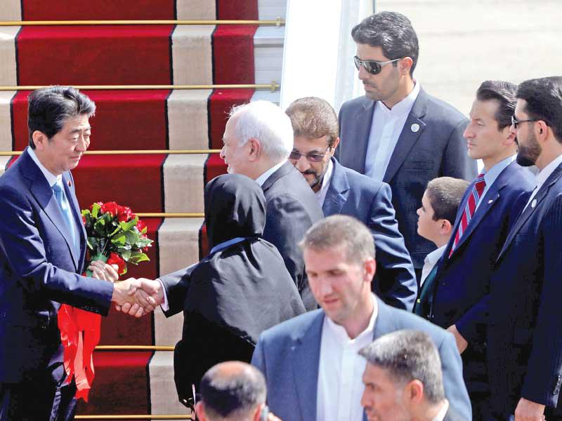 وزير الخارجية الإيراني محمد جواد ظريف مستقبلا رئيس الوزراء الياباني لدى وصوله إلى طهران أمس (أ ف ب)