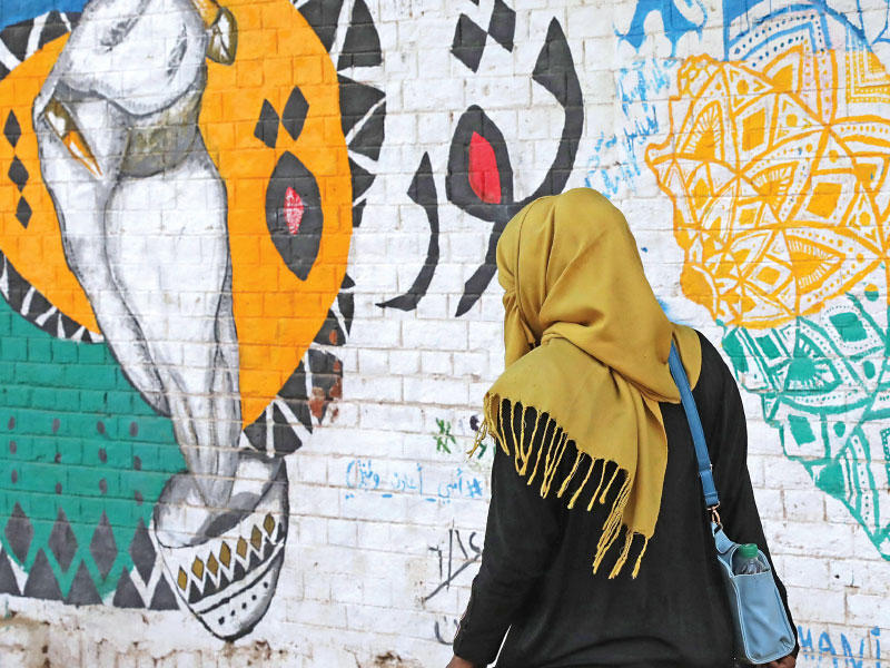 سودانية تمرّ قرب رسم غرافيتي في الخرطوم (اي بي ايه)