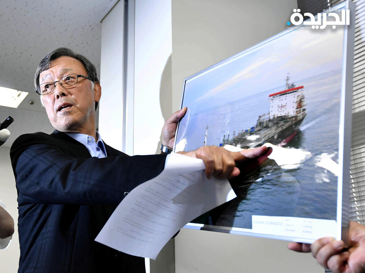 يوتاكا كاتادا، رئيس شركة الشحن اليابانية كوكوكا سانغيو، مع صورة لسفينة كوكوكا