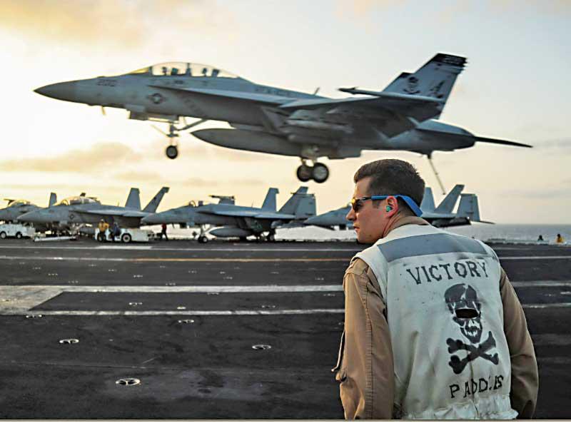عسكري أميركي يشاهد مقاتلة F18 تهبط على متن الحاملة «أبراهام لينكولن» التي كانت أخيراً في المنطقةt(الأسطول الخامس)