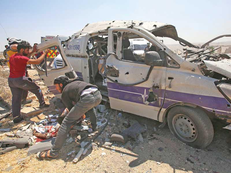 سوريون يساعدون مسعفاً أصيب بغارة استهدفت سيارته في معرة النعمان أمس   (أ ف ب)