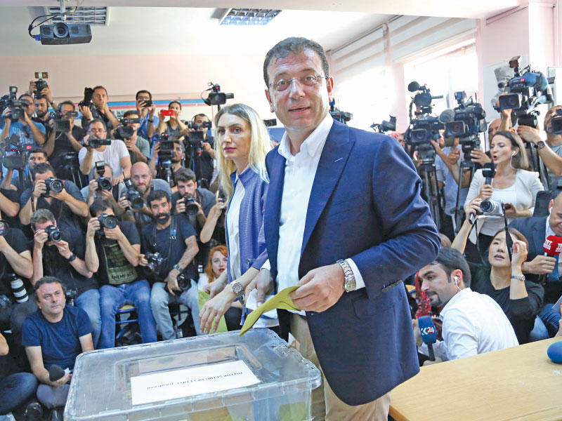 إمام أوغلو يدلي بصوته وتبدو زوجته بقربه  (رويترز)