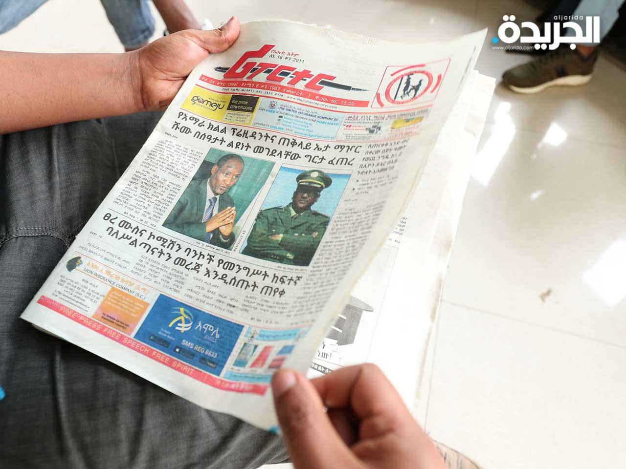 رجل إثيوبي يقرأ صحيفة تحمل صورًا لرئيس ولاية أمهرة أمباتشو ميكونين ، الذي قُتل في مدينة بحر دار الرئيسية ، ورئيس أركان الجيش سيير ميكونين