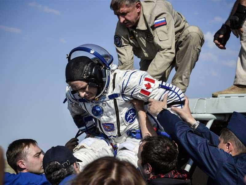 موظفو الخدمات الأرضية يساعدون ديفيد سانت جاك من وكالة الفضاء الكندية على الخروج من كبسولة Soyuz MS-11