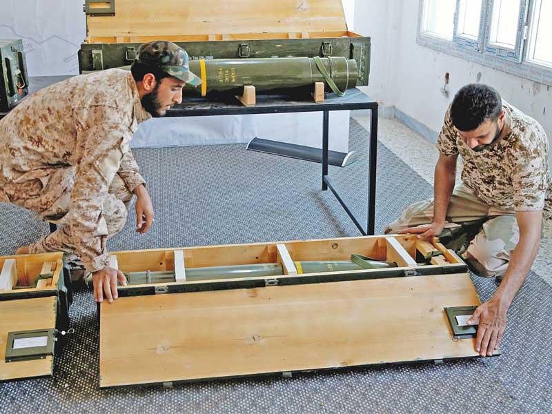 عنصران من حكومة «الوفاق» يعرضان في طرابلس صاروخاً تم اعتراضه ضمن شحنة أسلحة كانت في طريقها إلى قوات حفتر أمس الأول (رويترز)