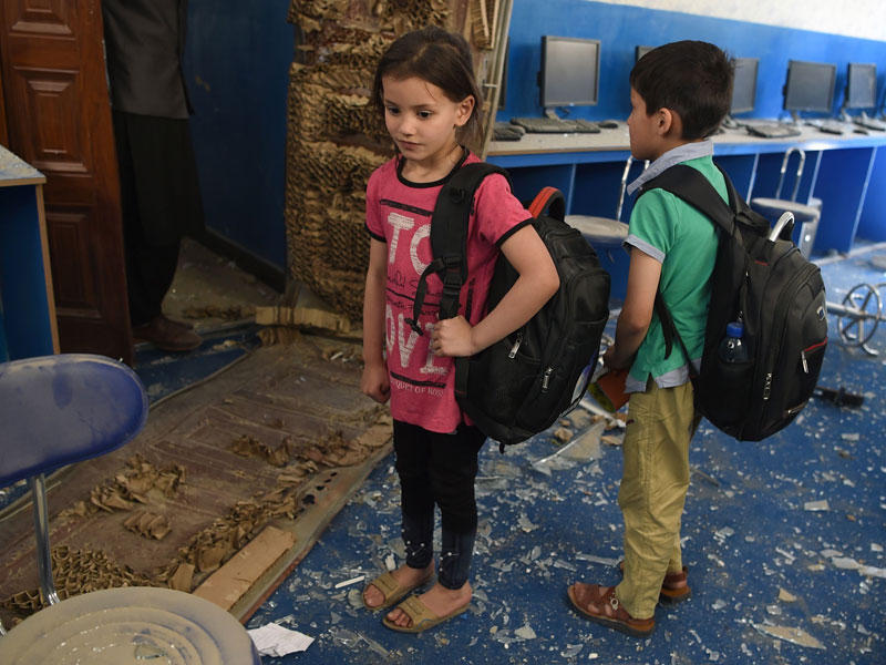 أطفال أفغان يقفون تحت الأنقاض في مدرسة بالقرب من موقع هجوم بسيارة مفخخة لطالبان في كابول