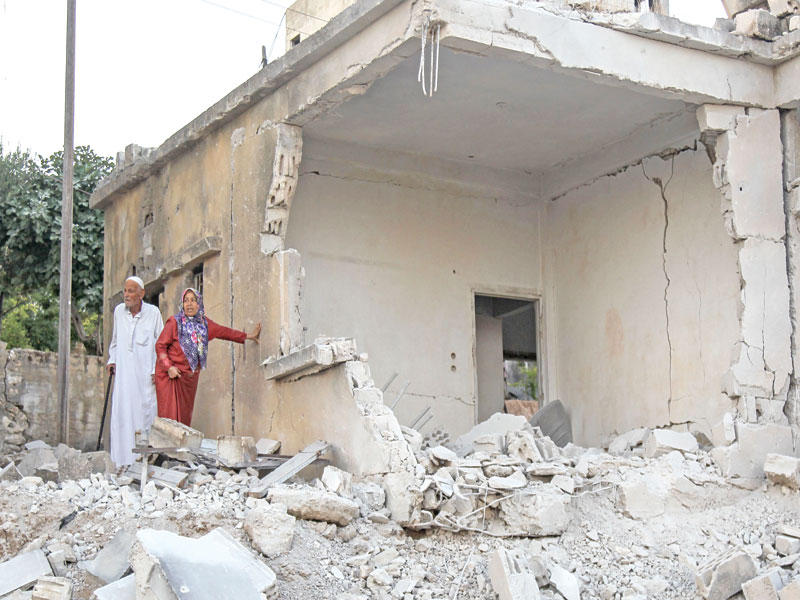 سوري وزوجته يتفقدان غارات النظام على منزلهما في بلدة محمبل أمس (أ ف ب)