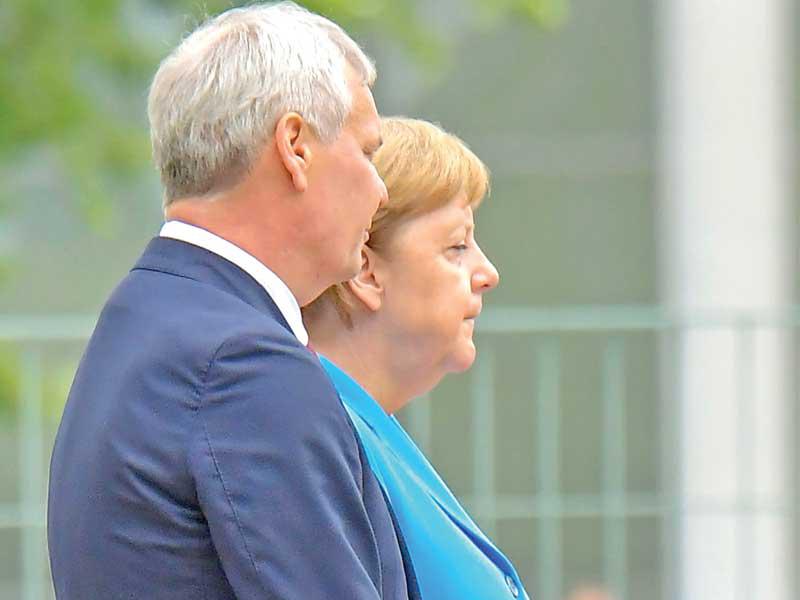 ميركل تحاول السيطرة على نفسها خلال استقبالها رئيس الوزراء الفنلندي ببرلين أمسt           (أ ف ب)