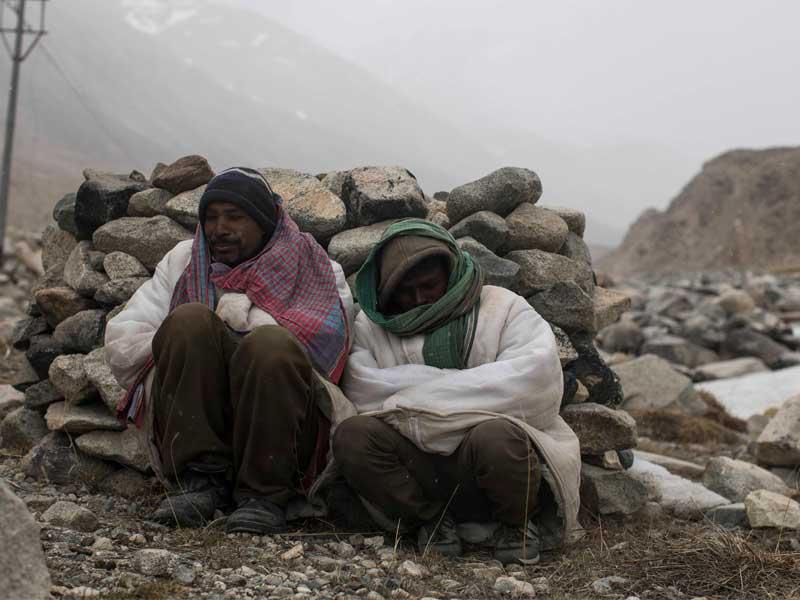 عاملان هنديان يتدفآن في ولاية كشمير وجامو أمسt (أ ف ب)