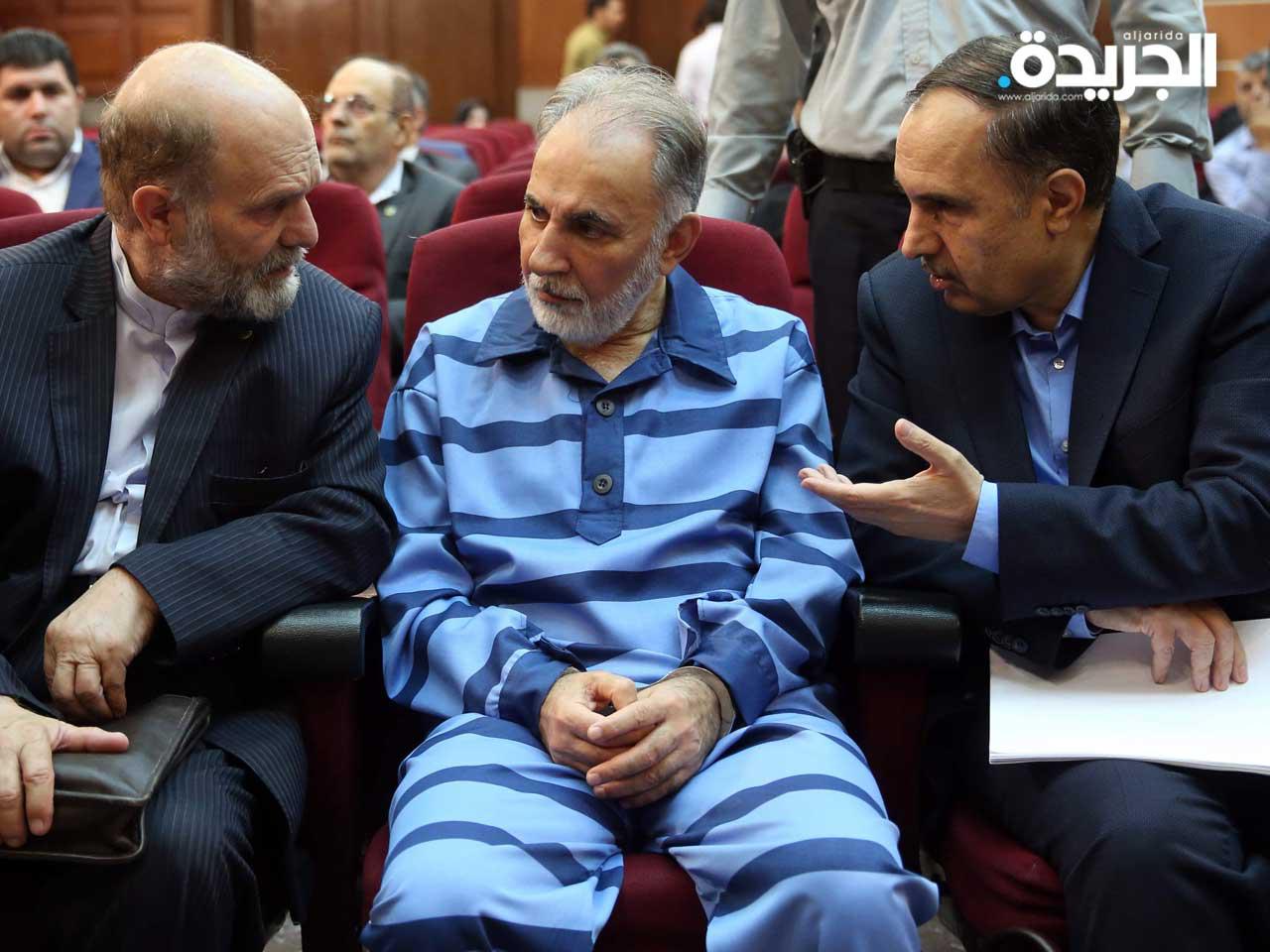 رئيس بلدية طهران السابق محمد علي نجفي المتهم بإطلاق النار على زوجته الثانية ، يتحدث مع محاميه قبل محاكمته أمام محكمة الجنايات الإيرانية