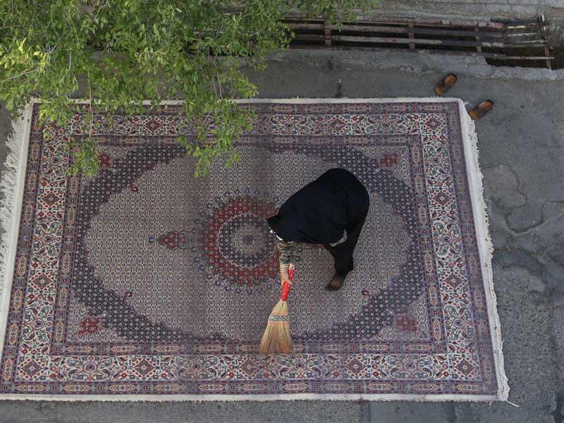 إيرانية تنظّف سجادة خارج مصنع سجاد فارسي في بيرجند (إرنا)n