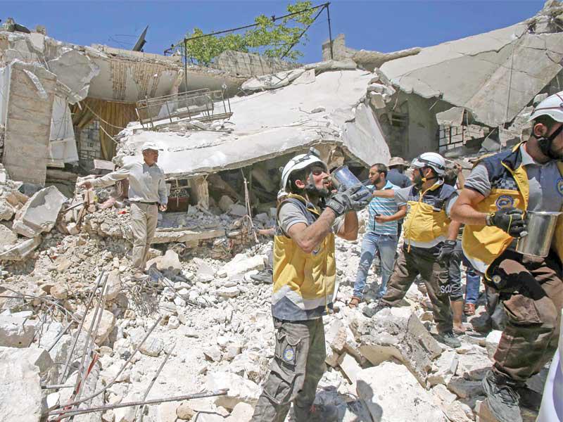 سوريون يبحثون عن ناجين تحت أنقاض مبنى دمرته غارة جوية على بلدة أورم الجوز جنوب إدلب أمس (أ ف ب)n