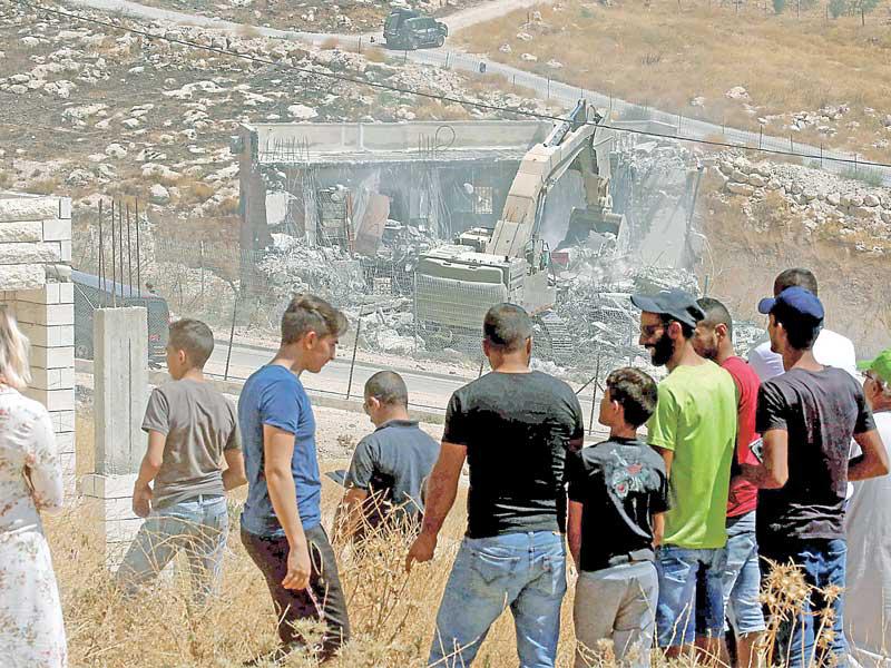 فلسطينيون يراقبون عملية الهدم التي باشرتها إسرائيل في منطقة صور باهر أمس (ا ف ب)n